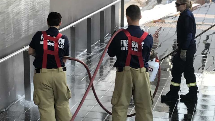 Two firefighters hosing a footpath