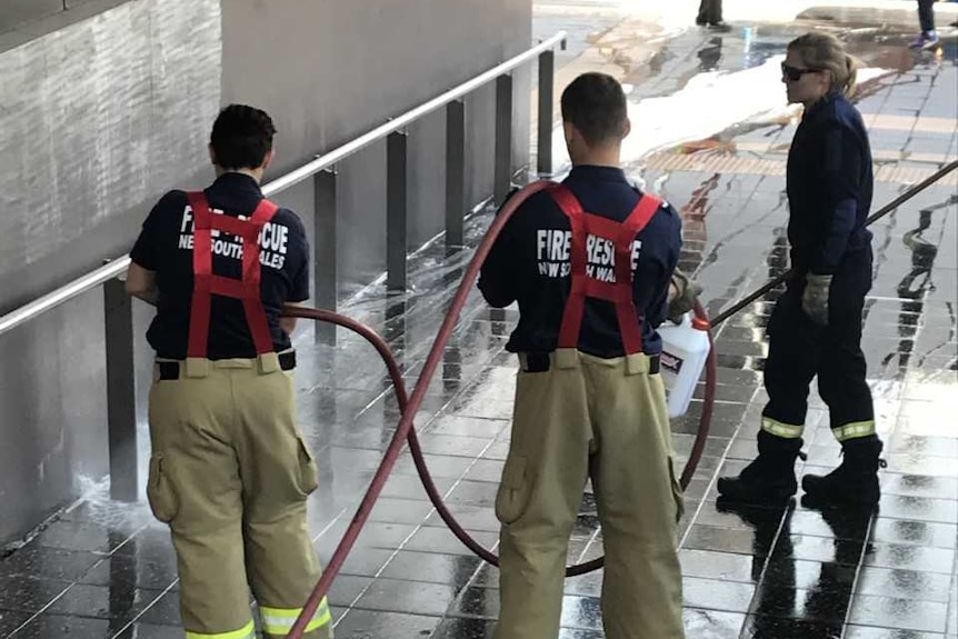 Two firefighters hosing a footpath