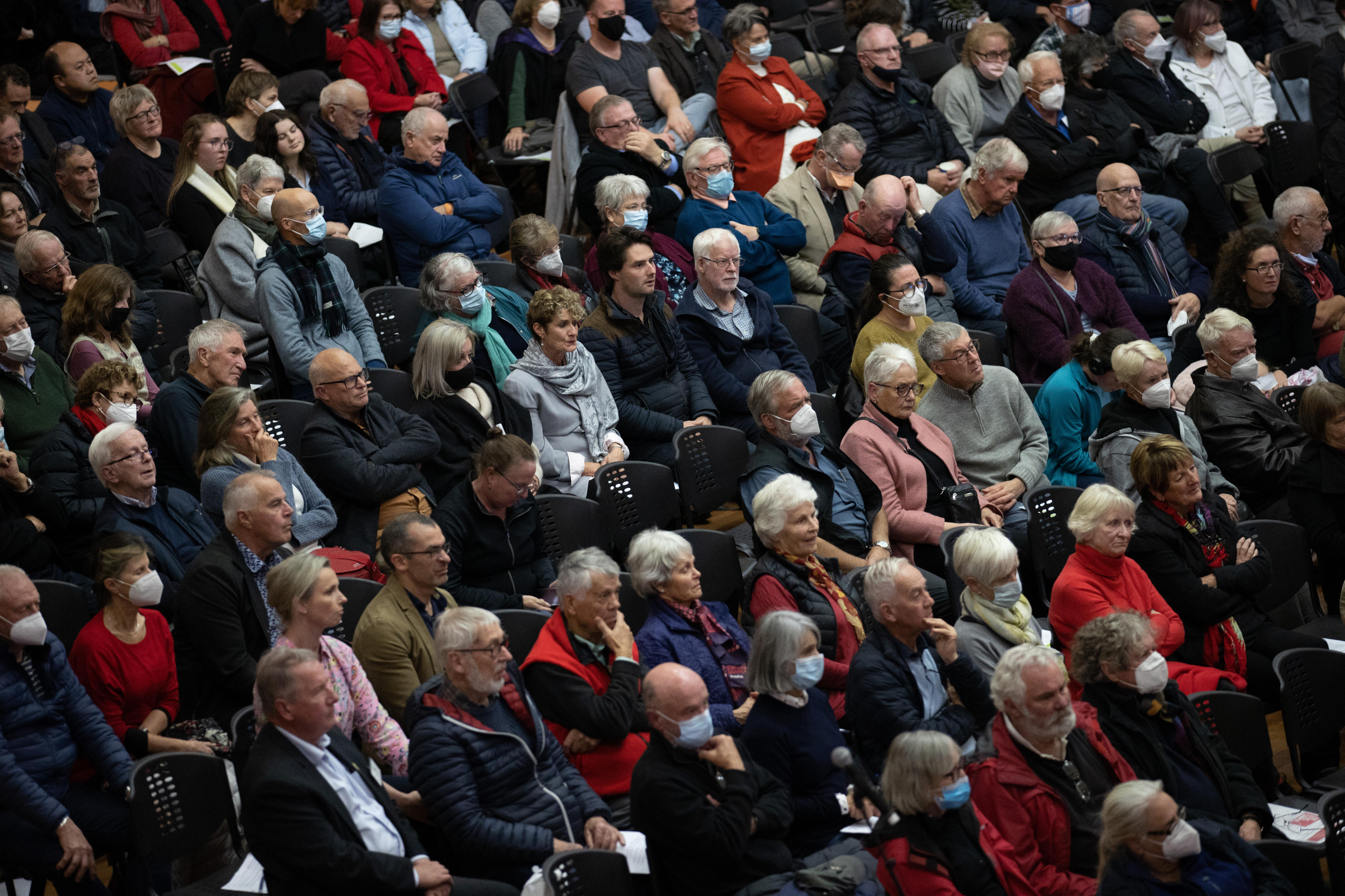 Dozens of people sit at a public meeting