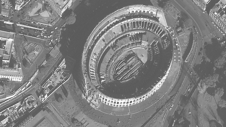 A satellite image of the Coliseum. People are dotted throughout the streets surrounding it.