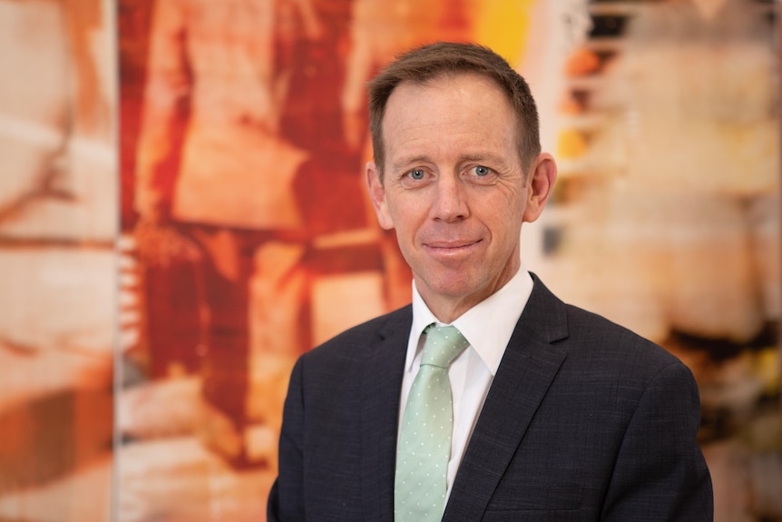 A man wearing a green tie smiles for the camera 