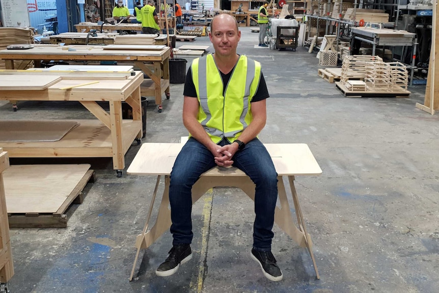 Jeremy Fleming sits on a wooden table.