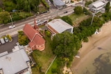 An aerial view of a church and church hall by the water's edge.
