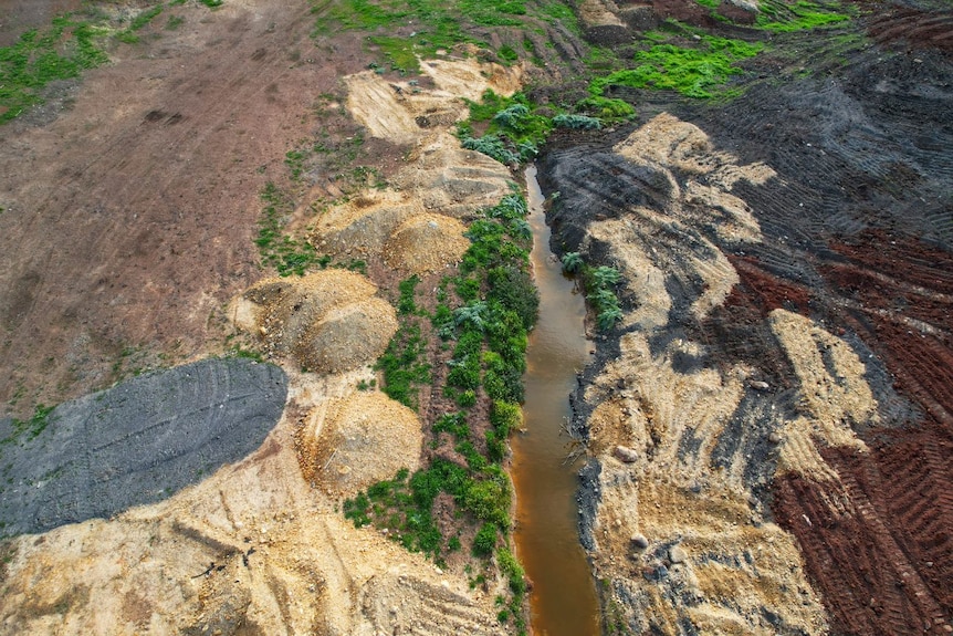 A creek flows through the middle of the area where soil covers grasslands