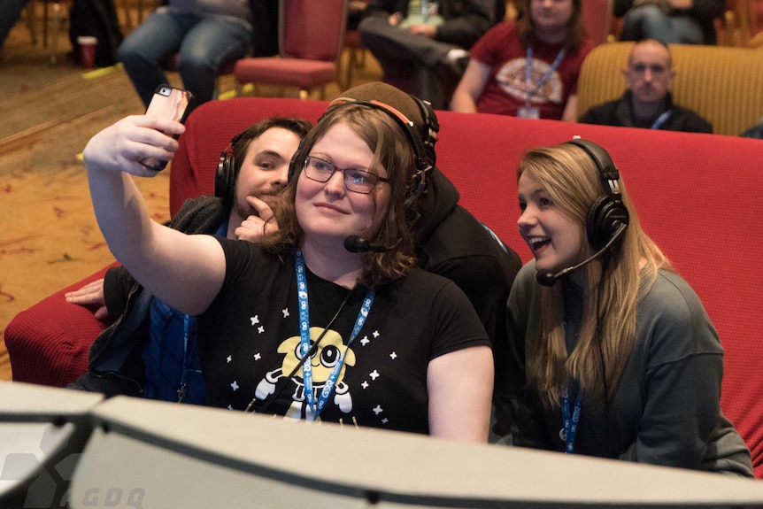 Four people huddle on a couch and take a selfie