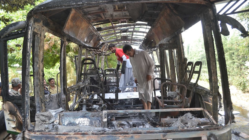Pakistani security personnel inspect a burnt university bus after a bomb blast in Quetta.
