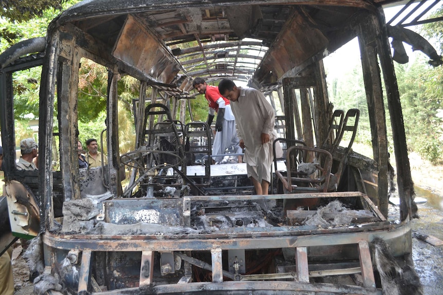 Pakistani security personnel inspect the burnt university bus.