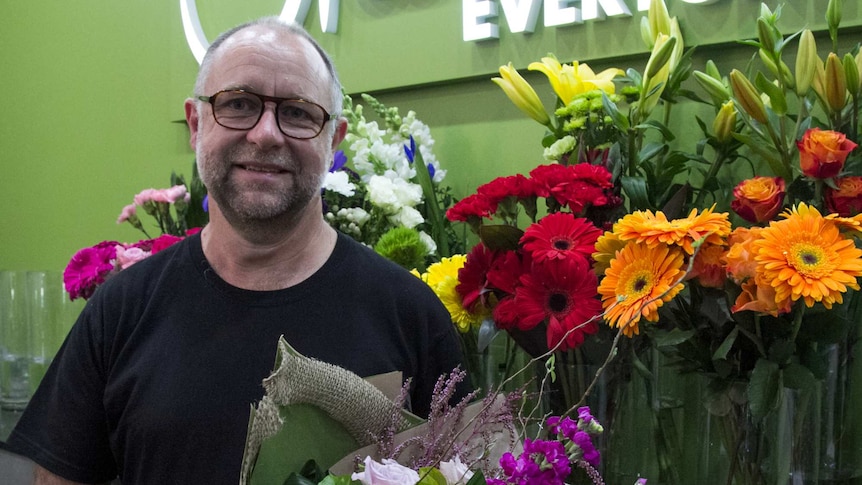 Jock Brown standing in front of flowers