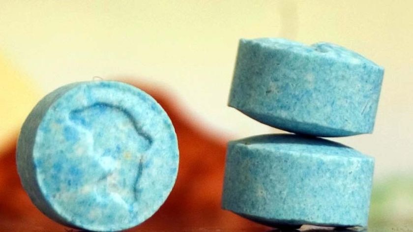 Ecstasy pills sit on a desk.