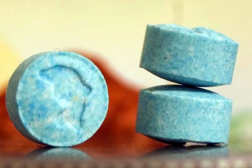 Ecstasy pills sit on a desk.