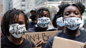 African-American protesters wear masks with "I can't breathe" written on them.