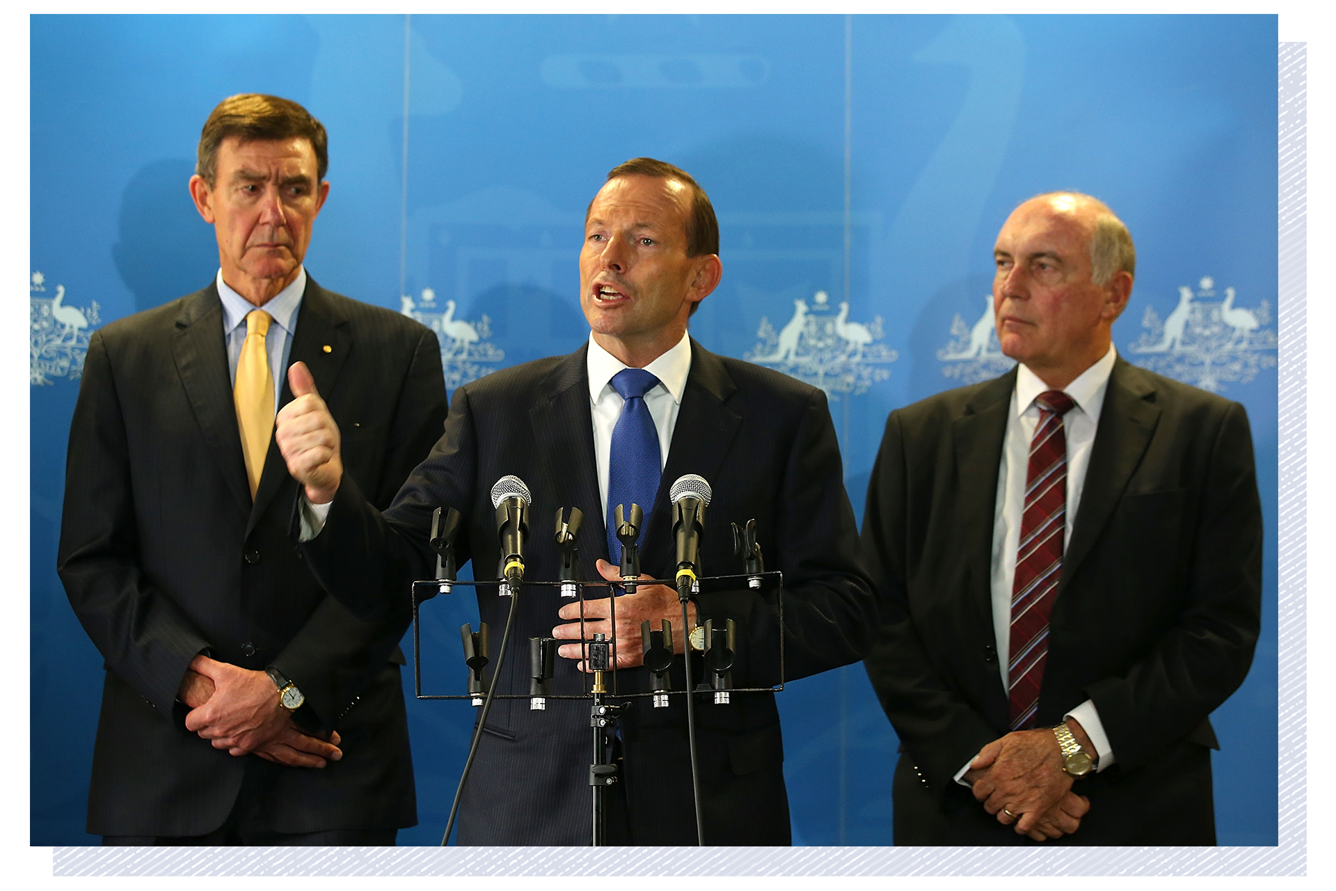 Dressed in suits and tie, Tony Abbott speaks at a press conference, flanked by Angus Houston and Warren Truss.