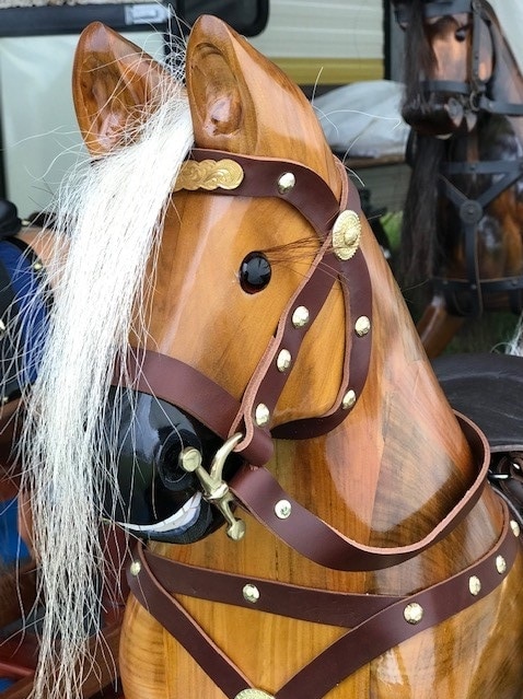A close up shot of a rocking horse, showing its glass eyes, mane and halter.