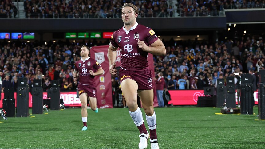 A Queensland male State of Origin player runs onto the field at Adelaide Oval.