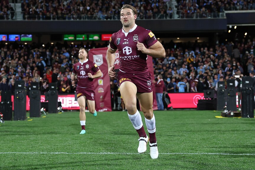 A Queensland male State of Origin player runs onto the field at Adelaide Oval.