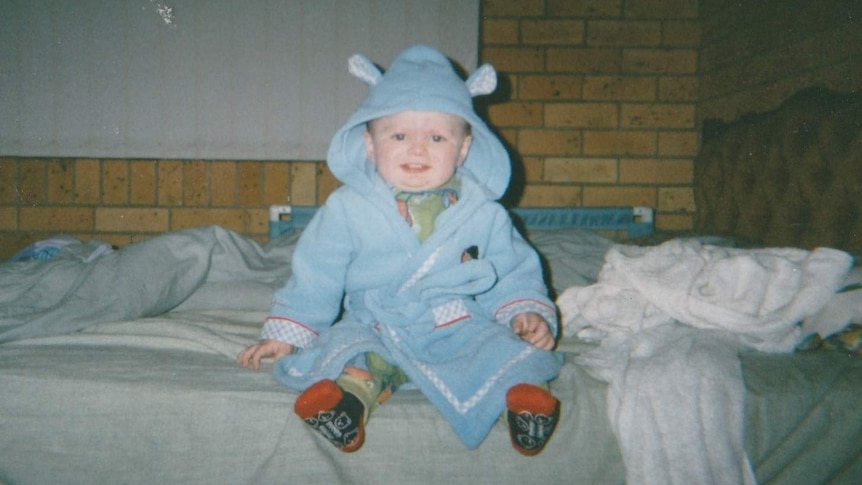 Toddler in blue dressing down with a hood.