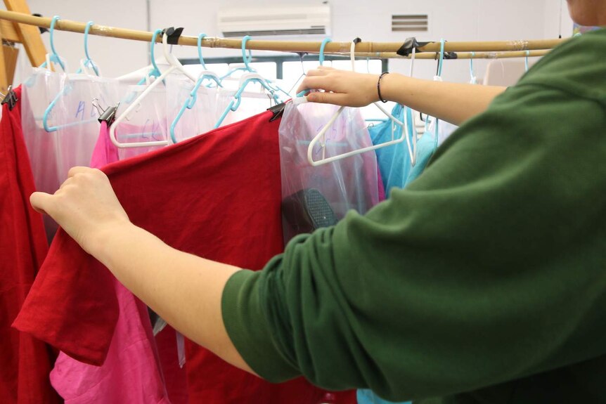 A woman in DPFC sorts through a rack of brightly-coloured costumes.