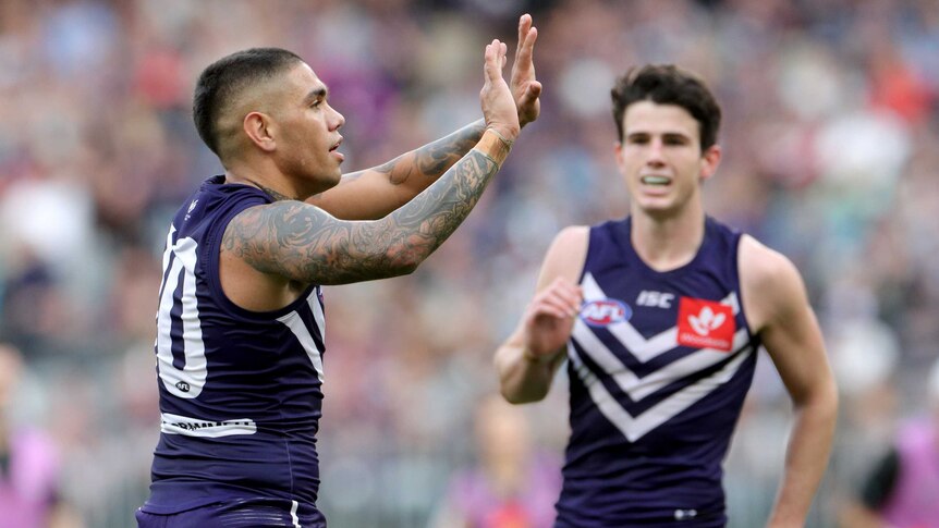 An AFL goalscorer looks to high-five a teammate in celebration.