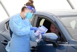 A female nurse doing a covid test to a man in a car.