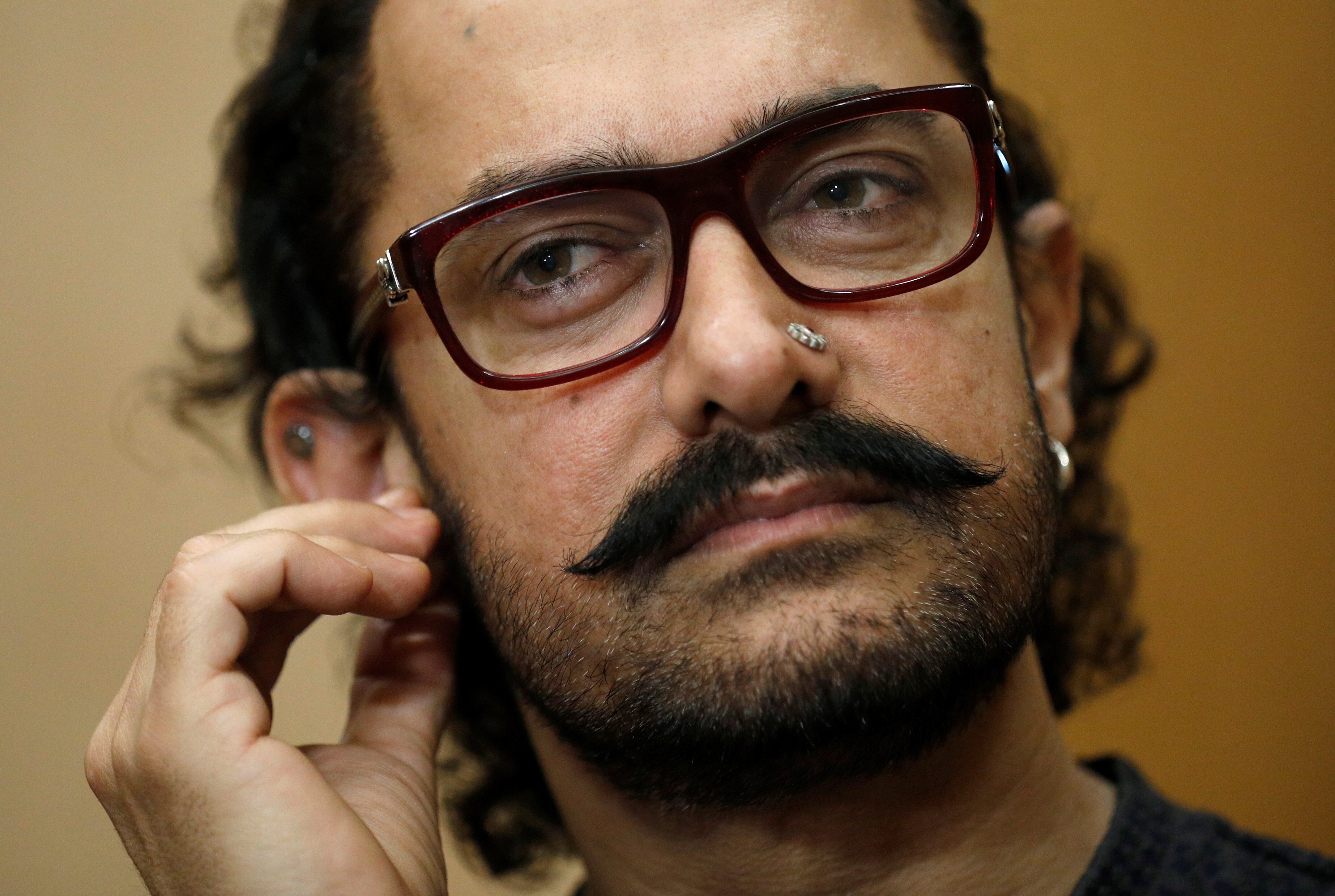 A man plays with his earring while looking at something out of shot