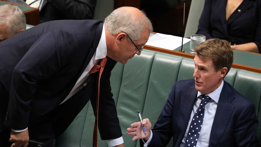 Scott Morrison leans over Christian Porter as they talk during Question Time