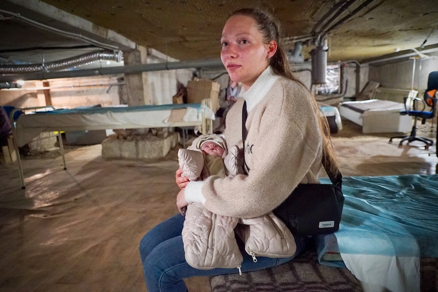 A young woman cradles a young baby inside the basement of a hospital.