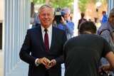 Former WA premier Colin Barnett walks outside the ABC buildings, surrounded by TV camera operators and photographers.