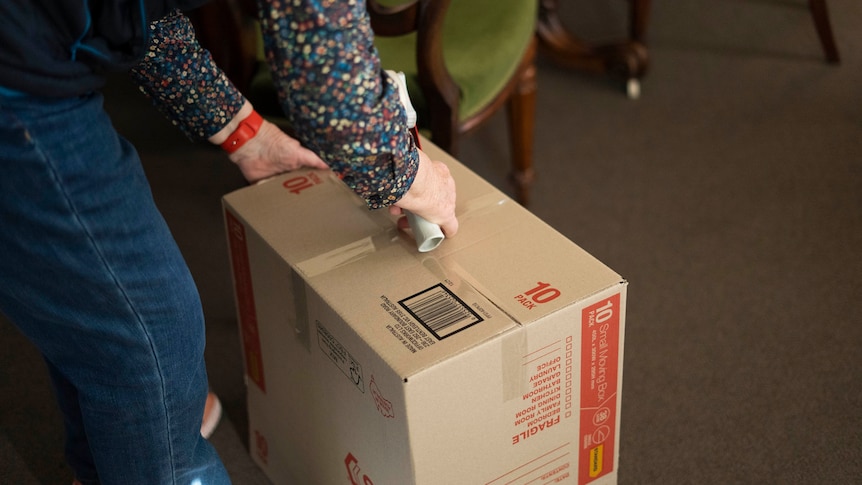 Person taping up a cardboard moving box.