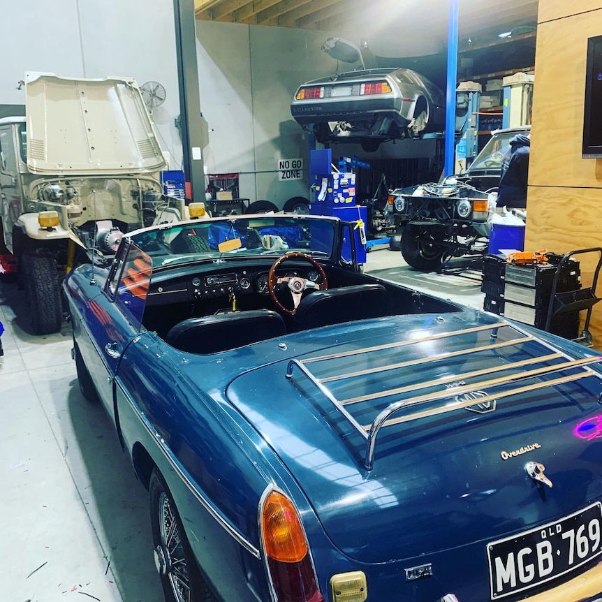 A blue MG roadster in a workshop