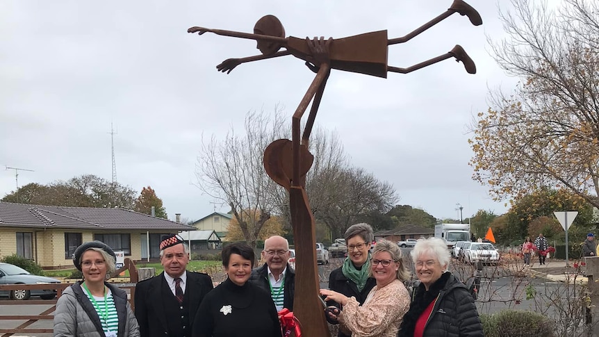 A group of people Sstanding around a sculpture.