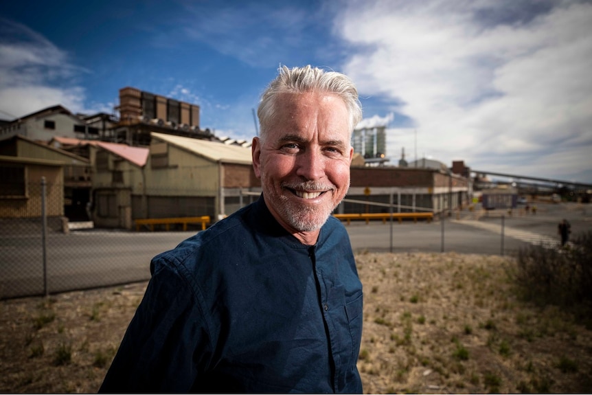 A man with silver hair smiles as he looks to the right