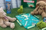 Two teddy bears sit in a driveway playing scrabble.