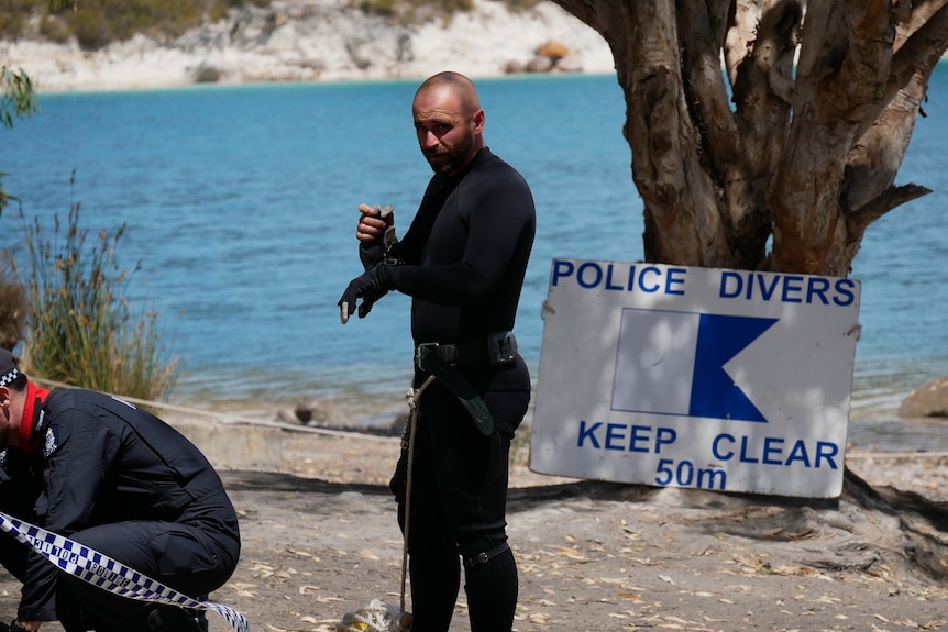 A police diver stands in front of a sign.