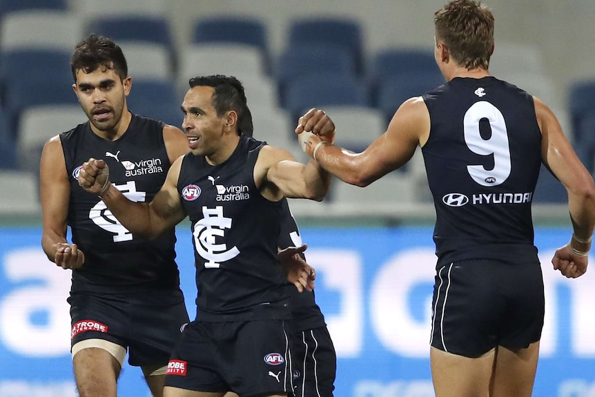 Eddie Betts celebrates a goal by bumping fists with Jack Martin and Patrick Cripps.