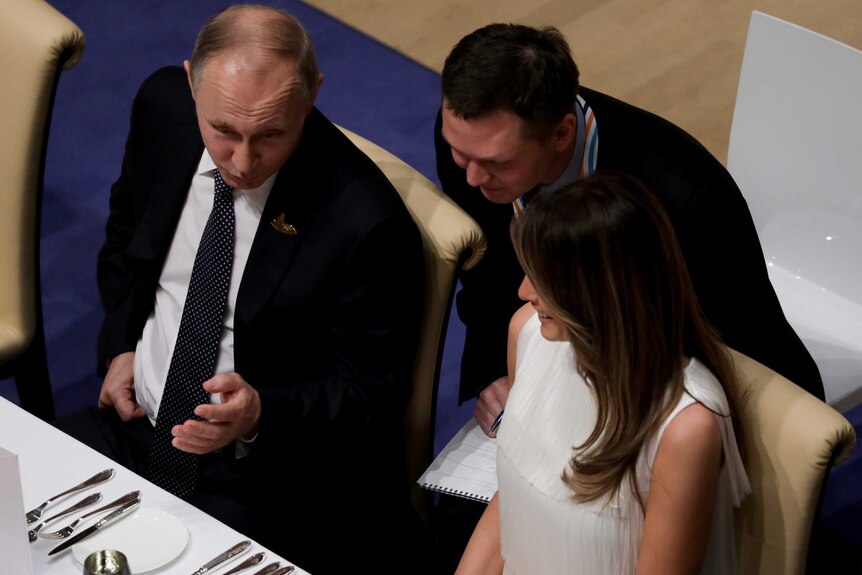 Russia's President Vladimir Putin talks to Melania Trump during on official dinner