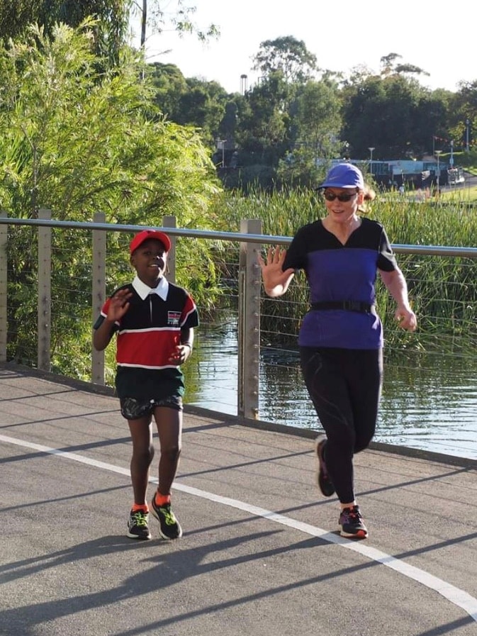Dr Jennie Wright (right) runs the parkrun course with her granddaughter. Both are waving at the camera.