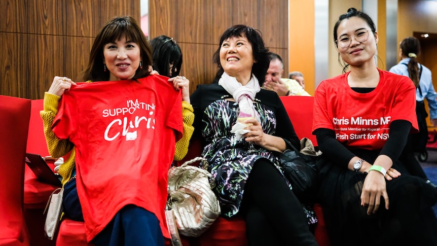 three women sitting down holding a labor party t-shirt