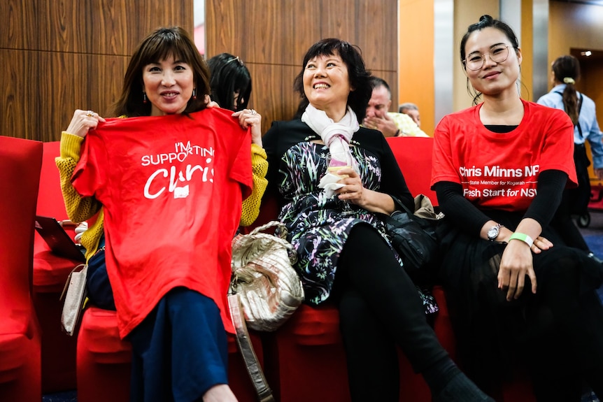 three women sitting down holding a labor party t-shirt