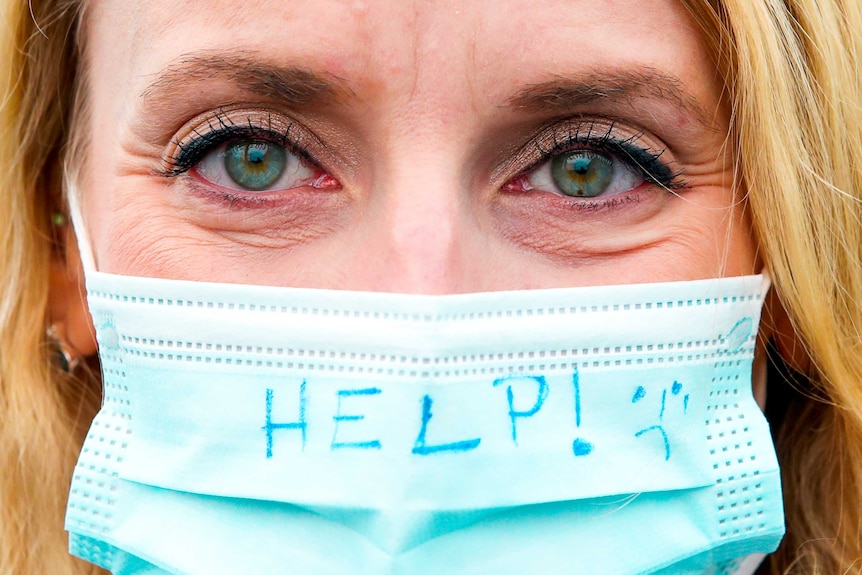 A woman in a medical face mask with 'help' written on it
