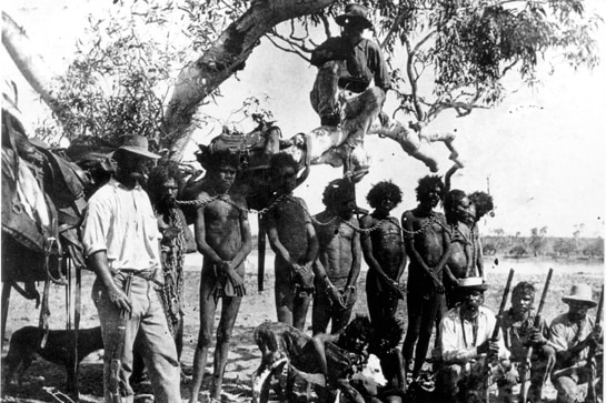 A black-and-white image of Indigenous people in chains and a policeman in 1890