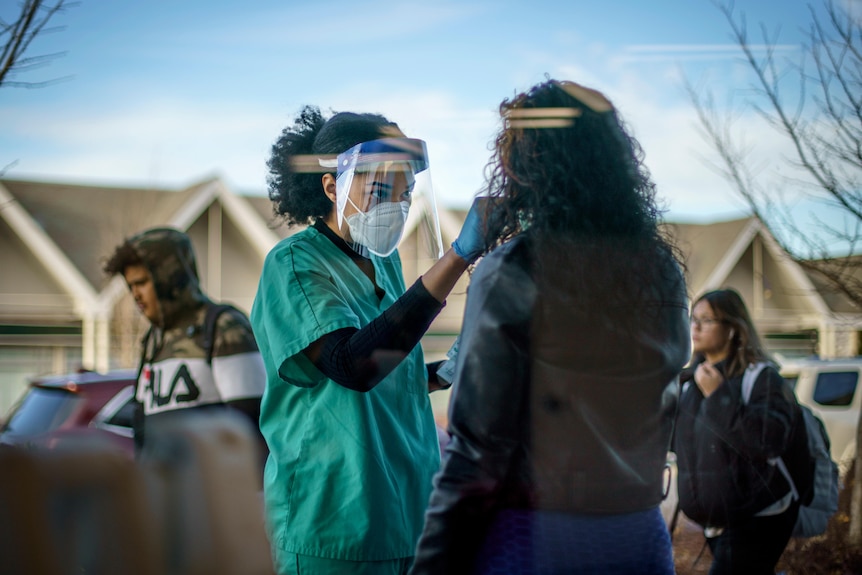 A healthcare worker takes a nasal swab from a woman