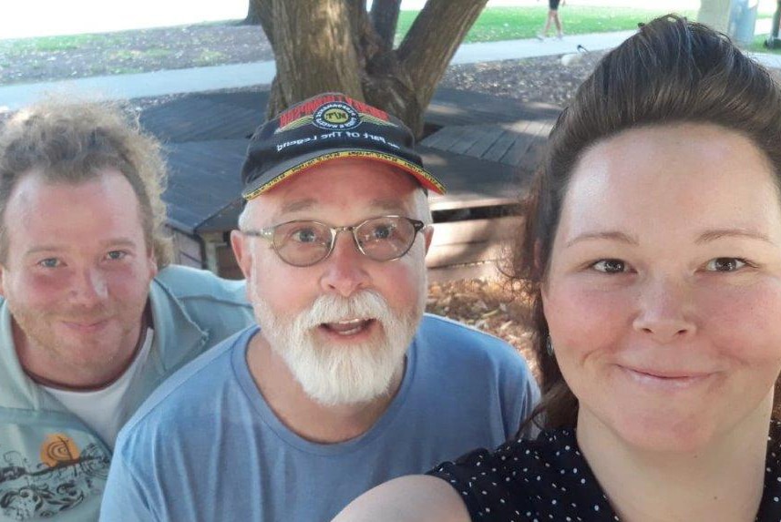 Three people pose for a selfie in a park.