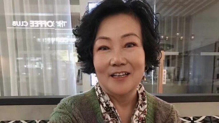 Photo of a Chinese woman with coffee and short hair with a smile.
