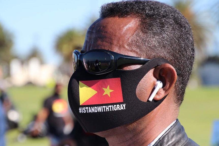 A man wears a black facemask with the Tigray flag reading #IStandWithTigray