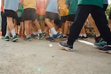 The legs of a group of school children dressed in uniforms.
