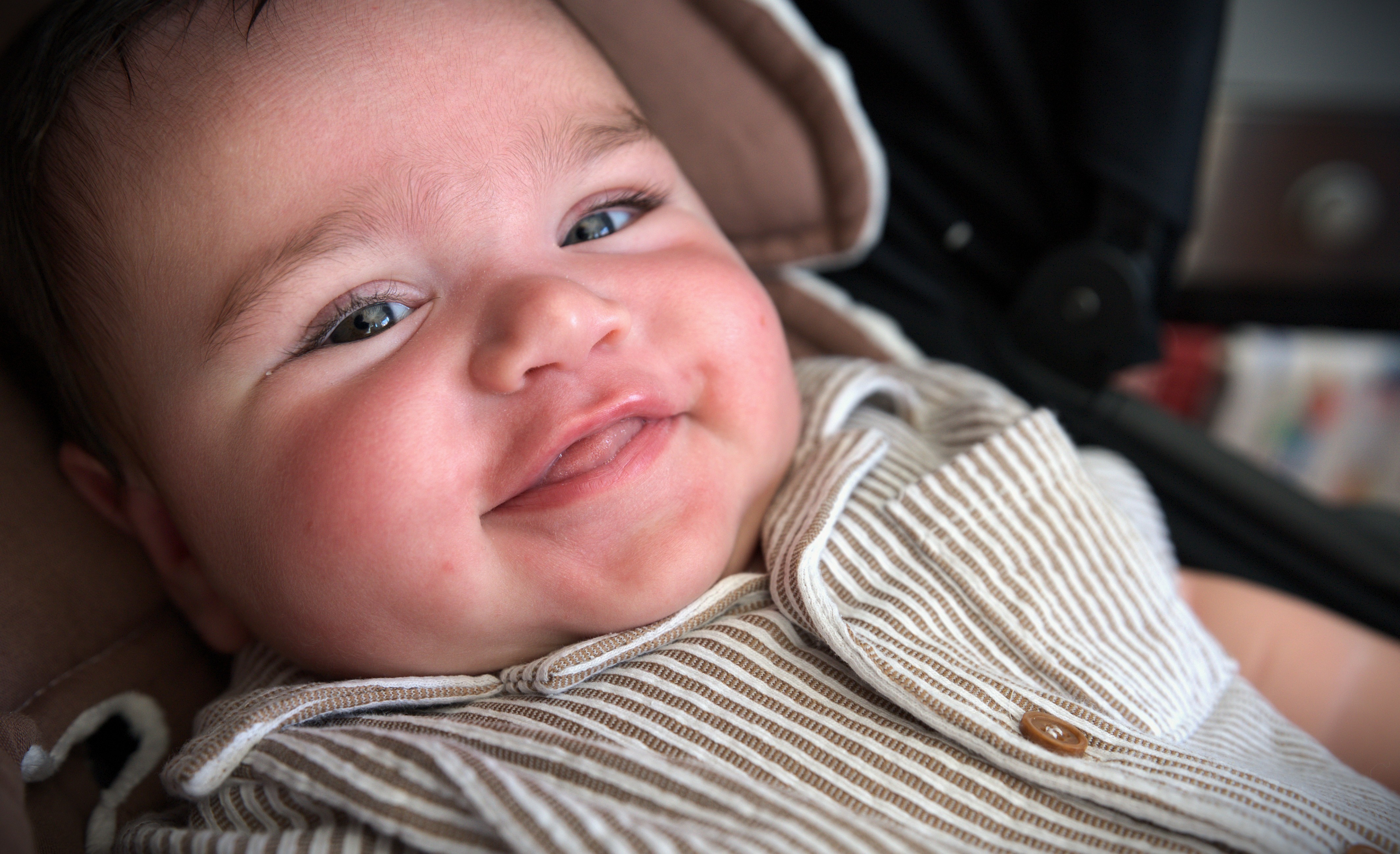 A close up of a smiling baby in a striped outfit 