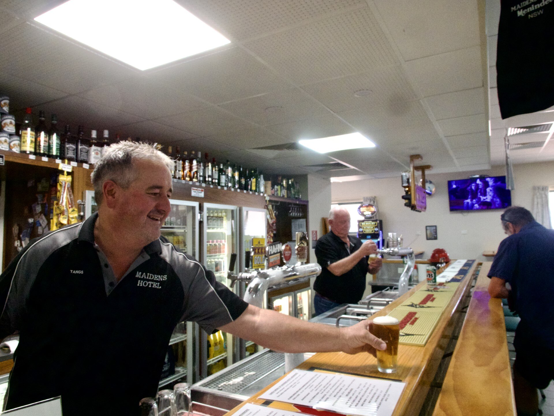 man serving a beer behind the bar of a pub 