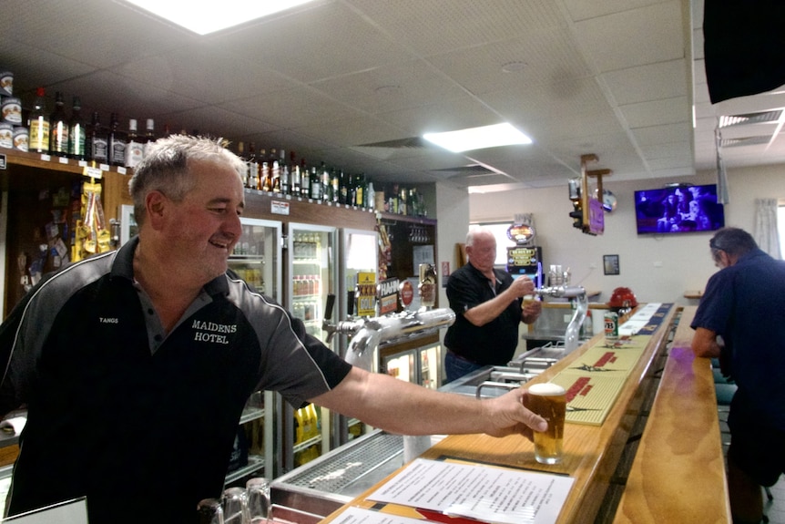 man serving a beer behind the bar of a pub 