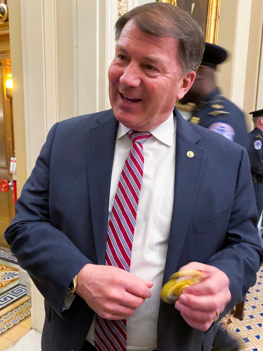 A man in a suit playing with a fidget spinner