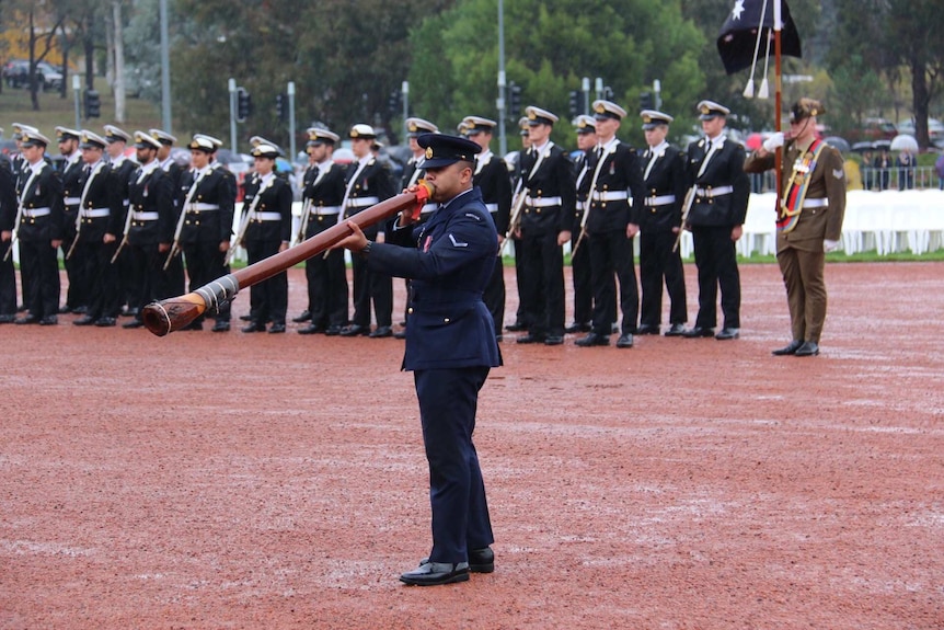 Didgeridoo being played on a wet parade ground at the Australian War Memorial